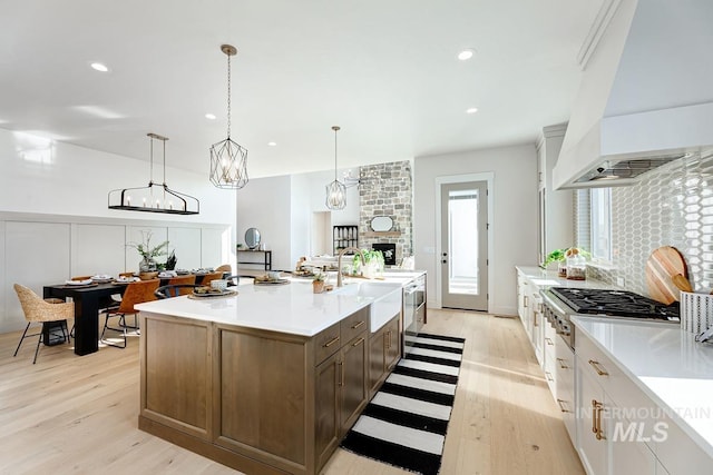 kitchen featuring custom range hood, light countertops, a sink, and stainless steel gas stovetop