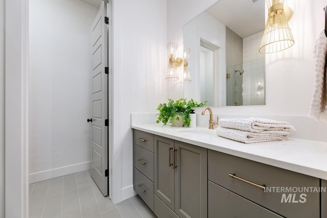 bathroom featuring tiled shower, vanity, baseboards, and tile patterned floors