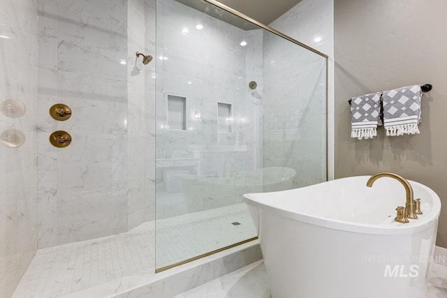 full bath featuring a freestanding tub, a marble finish shower, and marble finish floor