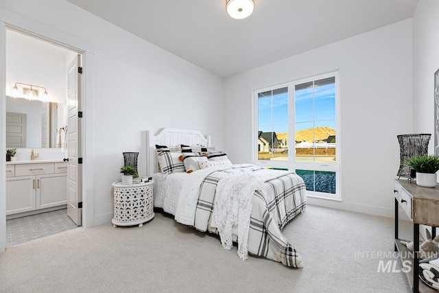 bedroom featuring light colored carpet, baseboards, and ensuite bathroom