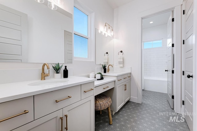 bathroom with a healthy amount of sunlight, shower / washtub combination, two vanities, and a sink