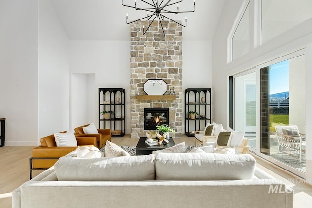 living area with baseboards, a chandelier, wood finished floors, a fireplace, and high vaulted ceiling