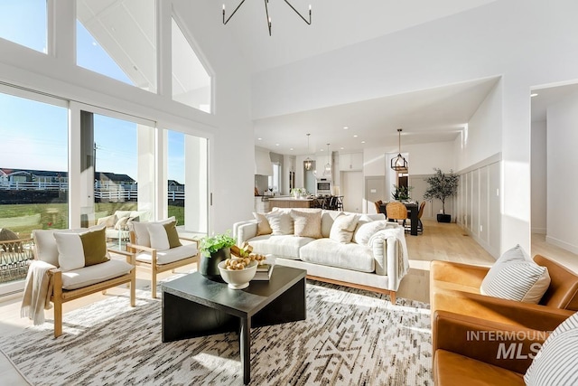 living room with a chandelier, light wood-style floors, and a towering ceiling