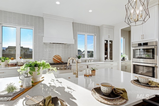 kitchen featuring white cabinets, a breakfast bar area, light countertops, double oven, and recessed lighting