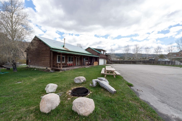 130 Valley Creek Rd, Stanley, ID 83278 - view of front of home with log siding, asphalt driveway, a porch, an outdoor fire pit, and an attached garage