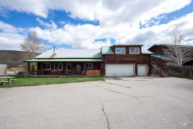 130 Valley Creek Rd, Stanley, ID 83278 - log home with a porch, metal roof, asphalt driveway, stairs, and a garage