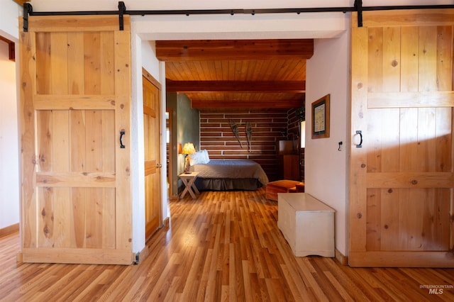 130 Valley Creek Rd, Stanley, ID 83278 - bedroom featuring a barn door, wood finished floors, and wooden ceiling with exposed beams
