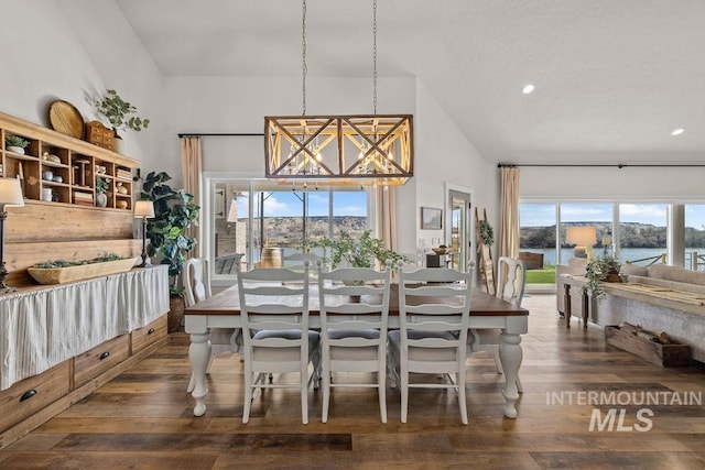 dining space featuring a notable chandelier, wood-type flooring, high vaulted ceiling, and a wealth of natural light