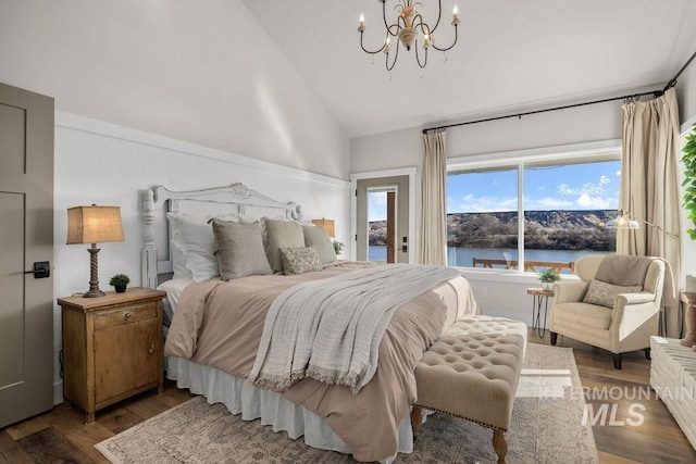 bedroom featuring wood finished floors, a water view, access to exterior, high vaulted ceiling, and a notable chandelier