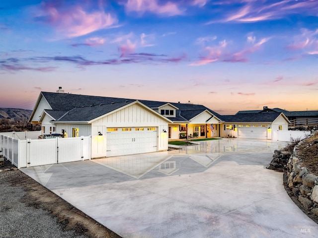 modern farmhouse featuring a garage, concrete driveway, a gate, fence, and board and batten siding