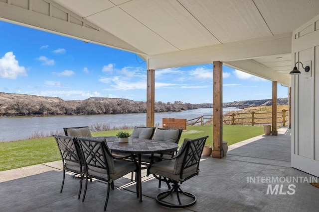 view of patio / terrace featuring outdoor dining area, a water view, and fence