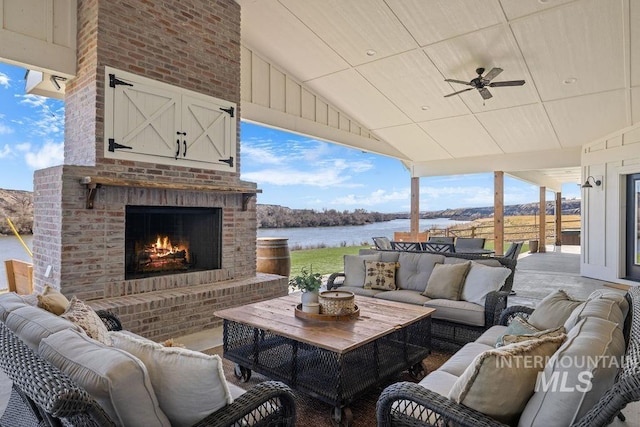 view of patio / terrace featuring a water view and an outdoor living space with a fireplace