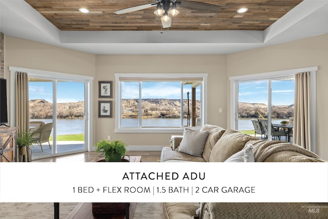 living area featuring a wealth of natural light, wooden ceiling, and a raised ceiling