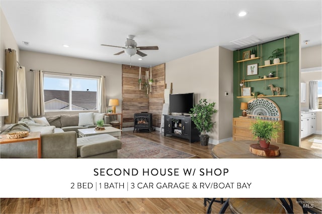 living room featuring recessed lighting, visible vents, a ceiling fan, a wood stove, and wood finished floors