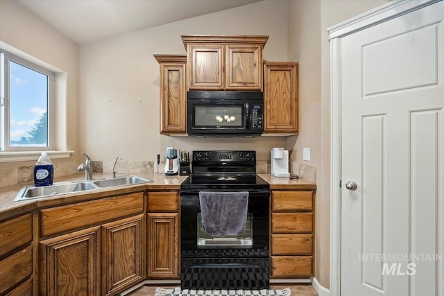 kitchen featuring lofted ceiling, a sink, black appliances, light countertops, and brown cabinets