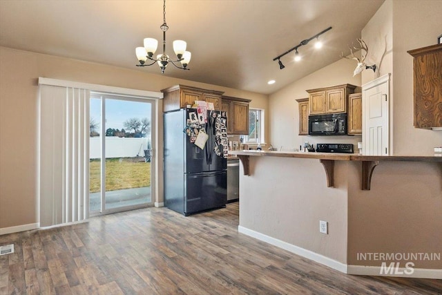 kitchen with black appliances, dark wood-style floors, an inviting chandelier, a breakfast bar area, and brown cabinetry