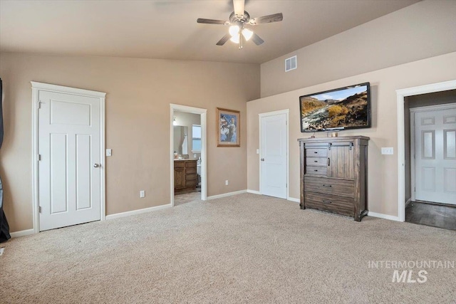 unfurnished bedroom with visible vents, baseboards, lofted ceiling, light carpet, and ensuite bath