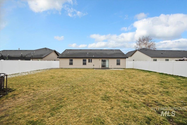 rear view of house featuring a yard and a fenced backyard