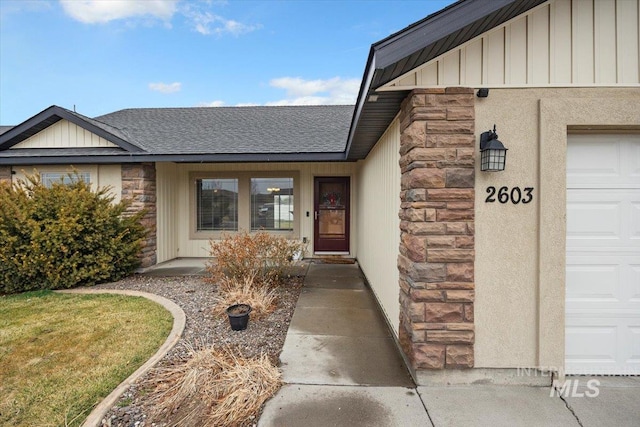 entrance to property featuring stone siding, board and batten siding, and roof with shingles