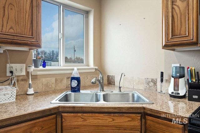 kitchen featuring brown cabinetry, light countertops, and a sink