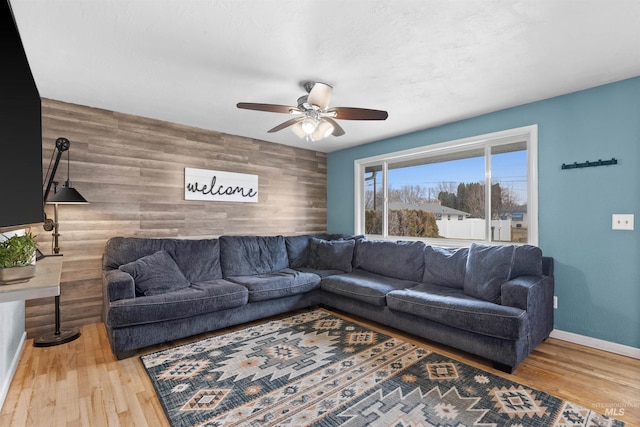 living room featuring hardwood / wood-style flooring, ceiling fan, and wood walls