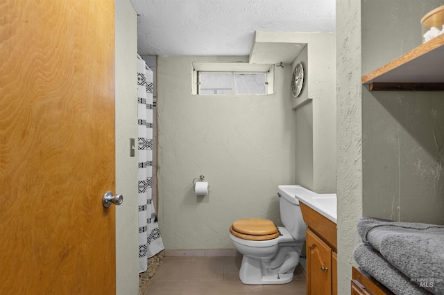 bathroom with tile patterned floors, vanity, toilet, and a textured ceiling