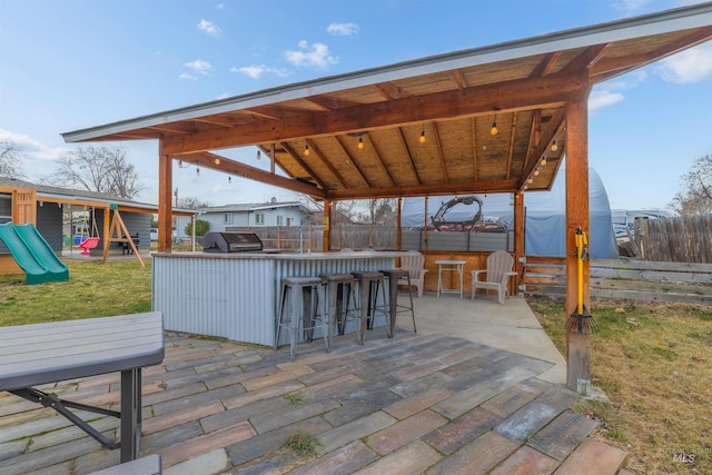 view of patio / terrace featuring a playground, a grill, and an outdoor bar