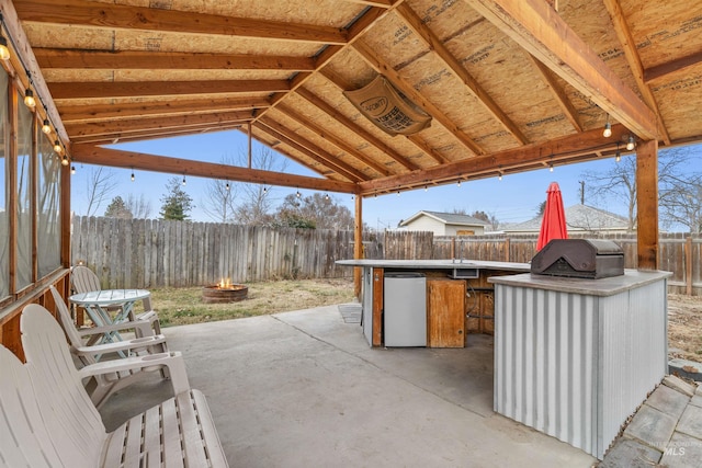 view of patio with a grill, an outdoor wet bar, area for grilling, and a fire pit