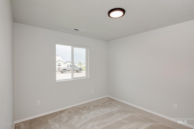 carpeted spare room featuring baseboards and visible vents