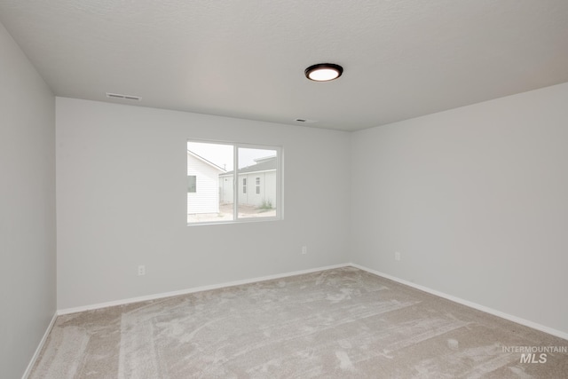 carpeted empty room featuring a textured ceiling