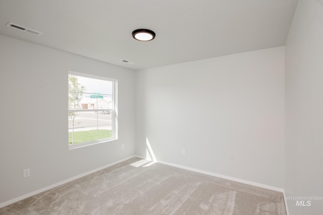 empty room featuring light carpet, visible vents, and baseboards