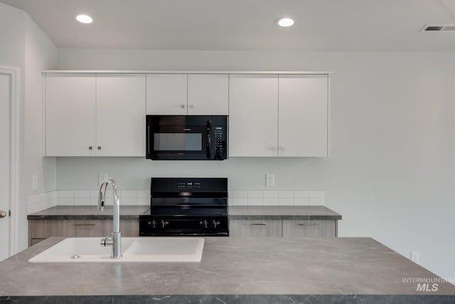 kitchen featuring dark countertops, visible vents, a sink, and black appliances