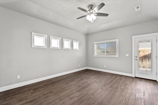 unfurnished room with ceiling fan, dark wood-type flooring, visible vents, and baseboards