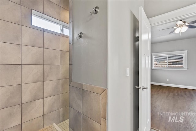 full bathroom with ceiling fan, baseboards, and tiled shower