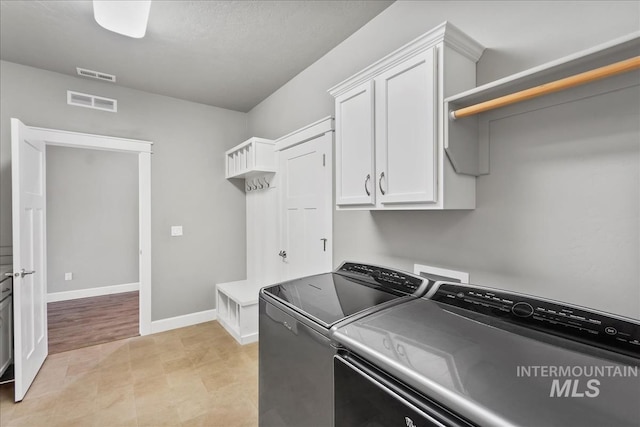 laundry room with baseboards, visible vents, cabinet space, and washing machine and clothes dryer