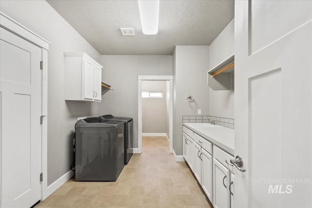 laundry area with a sink, visible vents, baseboards, independent washer and dryer, and cabinet space