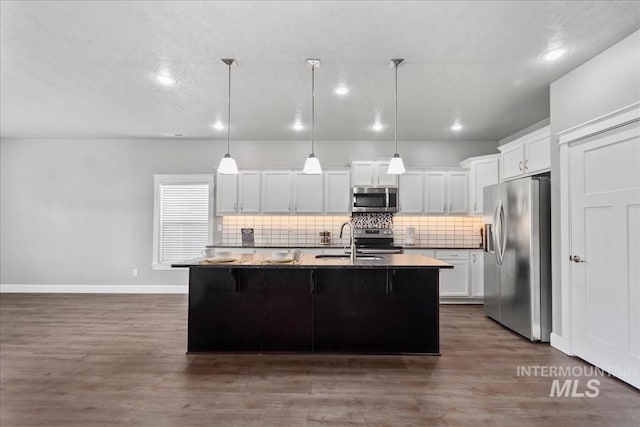 kitchen featuring stainless steel appliances, tasteful backsplash, dark wood-type flooring, and a sink