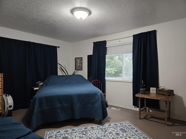 bedroom with finished concrete flooring, visible vents, and a textured ceiling