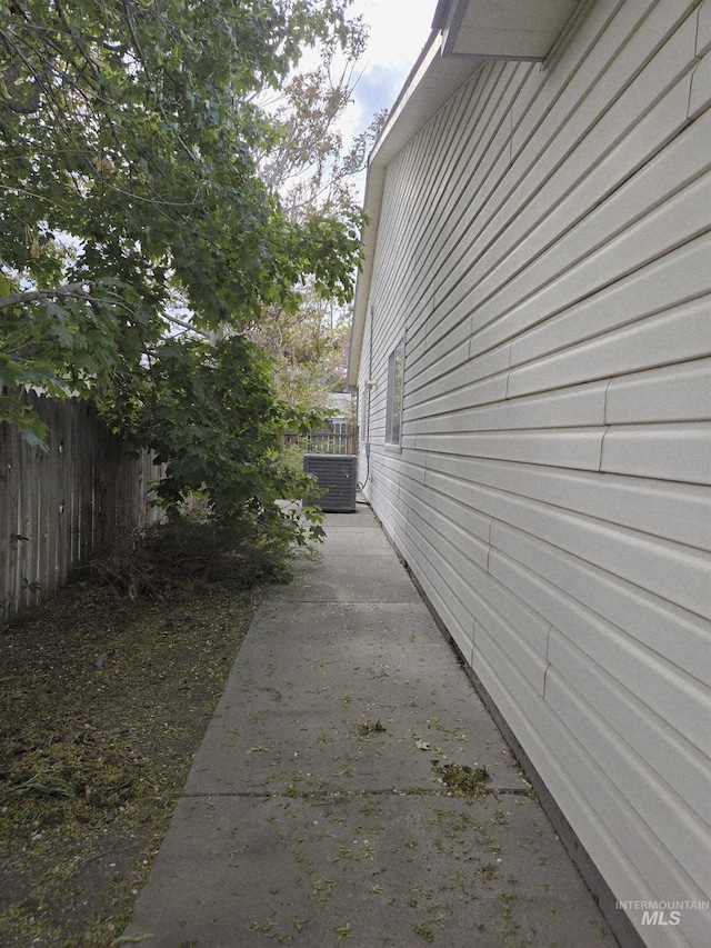 view of side of property with central AC unit, fence, and a patio
