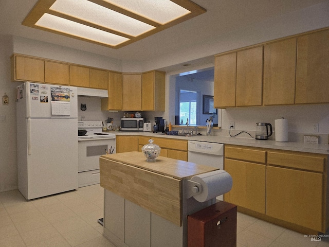 kitchen with a sink, white appliances, light floors, light countertops, and a kitchen island