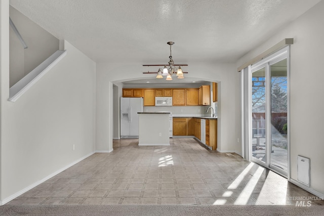 kitchen with white appliances, baseboards, a sink, pendant lighting, and a chandelier