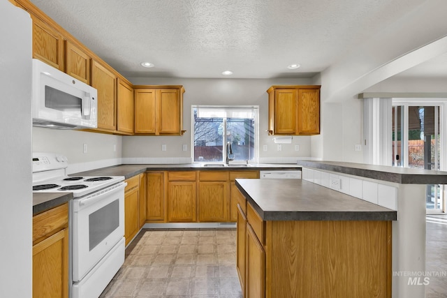 kitchen with a sink, white appliances, dark countertops, and light floors