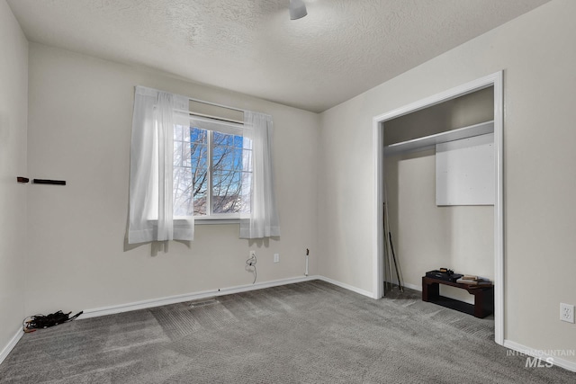 unfurnished bedroom with a textured ceiling, baseboards, and carpet floors