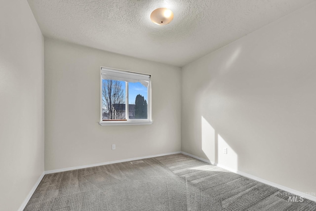 carpeted empty room with baseboards and a textured ceiling