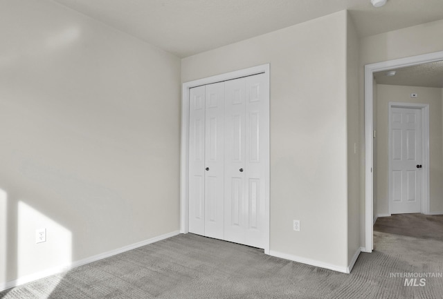 unfurnished bedroom featuring a closet, baseboards, and carpet floors