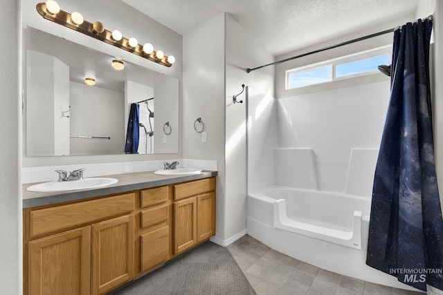 full bath featuring double vanity, a textured ceiling, shower / bath combo, and a sink