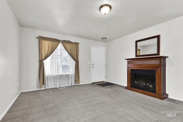 unfurnished living room with carpet, a fireplace, baseboards, and a textured ceiling