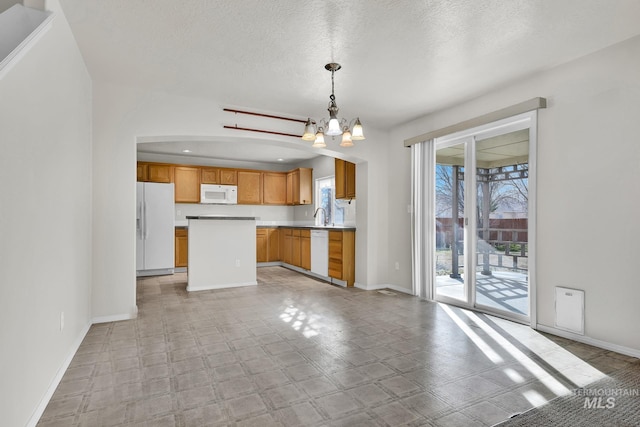 kitchen featuring white appliances, a center island, baseboards, and a chandelier