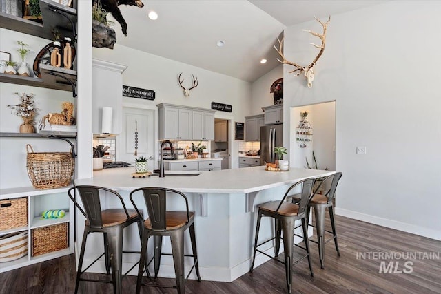 kitchen with stainless steel fridge, a breakfast bar, dark wood-type flooring, sink, and gray cabinets