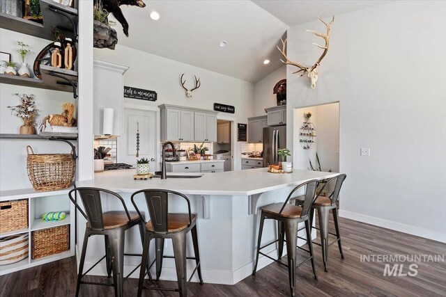 1418 N Birch St, Jerome, ID 83301 - kitchen featuring a sink, high vaulted ceiling, a peninsula, freestanding refrigerator, and a kitchen bar
